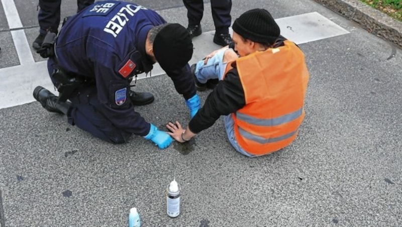 Polizisten lösen Kleber. (Bild: Zwefo)