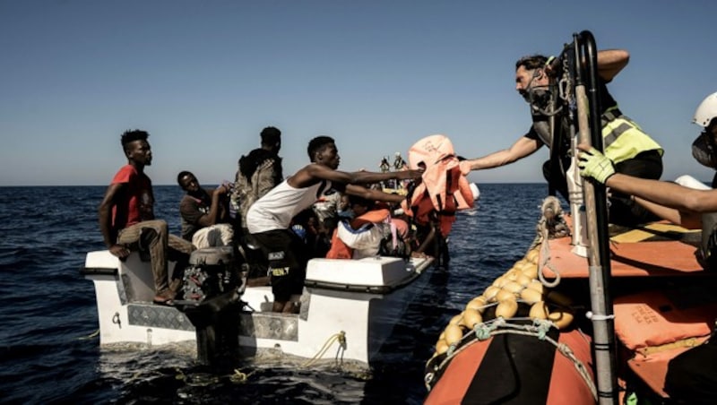 Mitglieder der Ocean-Viking-Crew bei der Aufnahme von gestrandeten Migranten (Bild: APA/AFP/Vincenzo CIRCOSTA)