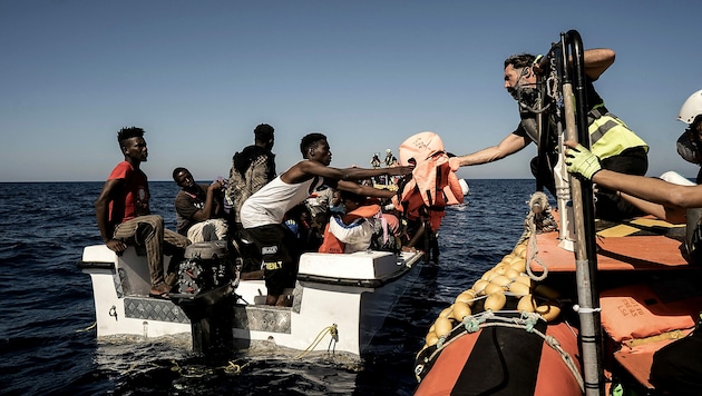 Mitglieder der Ocean-Viking-Crew bei der Aufnahme von gestrandeten Migranten (Bild: APA/AFP/Vincenzo CIRCOSTA)