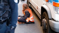 Eine festgenomme Aktivistin der "Letzten Generation" beim Klimaprotest auf der Straße (Bild: APA/AFP/MICHELE TANTUSSI)