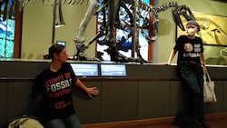Jelena Saf (re.) und Caroline Thurner, Aktivistinnen der Letzten Generation, klebten sich im Naturhistorischen Museum Wien (NHM) an einem Dinosaurier-Podest fest. (Bild: APA/LETZTE GENERATION ÖSTERREICH)