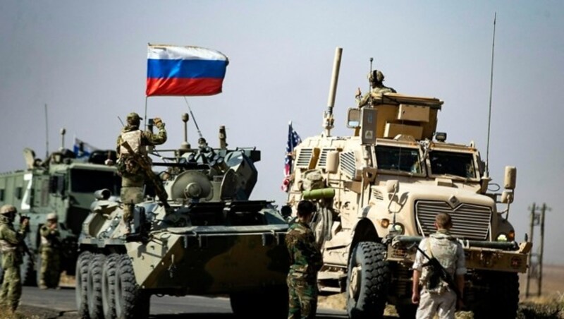 Russische und US-amerikanische Soldaten begrüßen sich während ihrer Patrouillen im Norden Syriens. (Bild: APA/AFP/Delil SOULEIMAN)