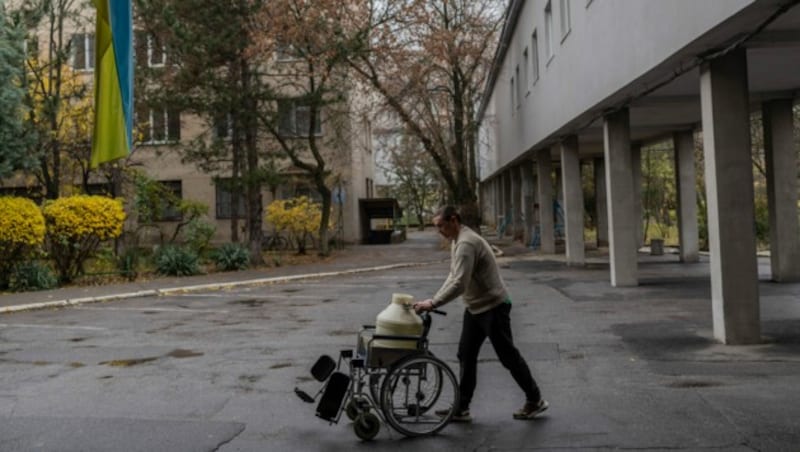 Ein Mann benutzt einen Rollstuhl, um Wasser in ein Krankenhaus in Cherson zu transportieren. (Bild: ASSOCIATED PRESS)