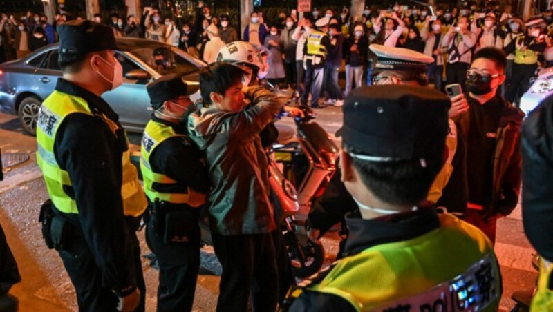 Polizisten in Schanghai nehmen einen Mann fest, der die Straße blockierte. (Bild: APA/AFP/Hector RETAMAL)