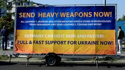 Dieser Banner auf einem Anhänger wirbt für schwere Waffen aus Deutschland. (Bild: APA/AFP/John MACDOUGALL)