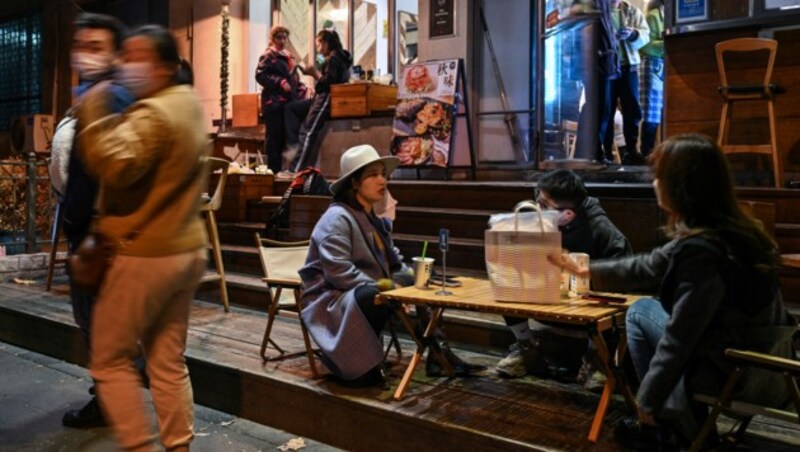 Lockerungen der Corona-Maßnahmen in China: Menschen stehen am 7. Dezember vor einem Restaurant im Jing‘an-Viertel in Shanghai. (Bild: APA/AFP/Hector RETAMAL)