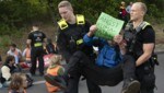 Berlin: Polizeibeamte tragen einen Demonstranten der Gruppe „Letzte Generation“ von einer Fahrbahn (Archivbild) (Bild: APA/dpa/Paul Zinken)
