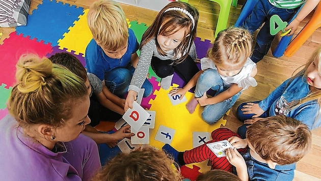 Kinder beim Spielen mit ihrer Pädagogin (Symbolbild) (Bild: oksix - stock.adobe.com)