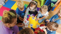 Kinder beim Spielen mit ihrer Pädagogin (Bild: oksix - stock.adobe.com)