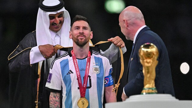 Qatar‘s Emir Sheikh Tamim bin Hamad al-Thani hängt Lionel Messi den Umhang um. (Bild: AFP or licensors)