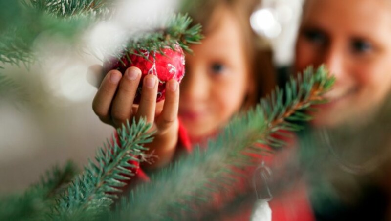 Für viele Menschen in Österreich ist erst Weihnachten, wenn der mit Weihnachtskugeln, Süßigkeiten und Kerzen geschmückte Tannenbaum erleuchtet wird. (Bild: Kzenon - stock.adobe.com)