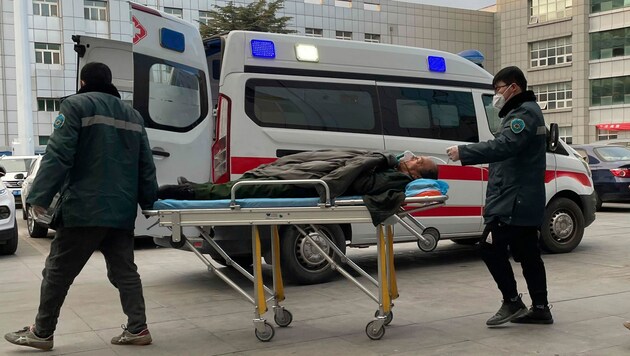 Medizinisches Personal schiebt einen Mann an einem Krankenwagen im Krankenhaus in der chinesischen Stadt Zhuozhou in der Provinz Hebei vorbei. (Bild: The Associated Press)