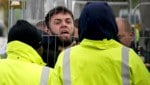 Erstaufnahmeeinrichtung Manston am Ärmelkanal: Ein Migrant, der versucht, mit Journalisten zu sprechen, wird von Mitarbeitern gegen einen Zaun gedrückt. (Bild: AP)