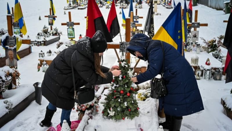 Angehörige dekorieren einen Weihnachtsbaum für einen gefallenen Soldaten in Lwiw. (Bild: AF)