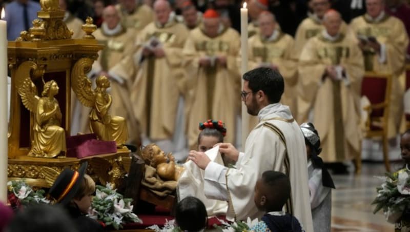 Ein Priester enthüllt eine Statue des Jesuskindes, während Papst Franziskus der Heiligabendmesse im Petersdom im Vatikan vorsteht. (Bild: ASSOCIATED PRESS)