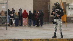 Ein Nationalgardist sichert einen Bereich ab, während Angehörige von Insassen vor dem Gefängnis auf Informationen warten. (Bild: AFP)