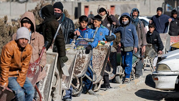 Poverty is also very high in Afghanistan despite the country's enormous natural resources. The picture shows children who have queued up at a food distribution point with wheelbarrows. (Bild: APA/AFP/Wakil KOHSAR)