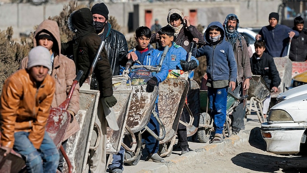 Die Armut ist in Afghanistan trotz enormer Bodenschätze sehr groß. Im Bild sieht man Kinder, die sich mit Scheibtruhen bei einer Essensausgabe angestellt haben. (Bild: APA/AFP/Wakil KOHSAR)