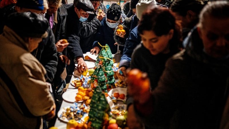 Ein weihnachtlich dekorierter Tisch mit Essen in einer sozialen Einrichtung in der umkämpften Stadt Bachmut (Bild: APA/AFP/Dimitar DILKOFF)