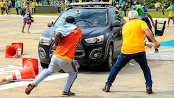 Demonstranten beim Angriff auf ein Polizeifahrzeug (Bild: APA/AFP/Sergio Lima)
