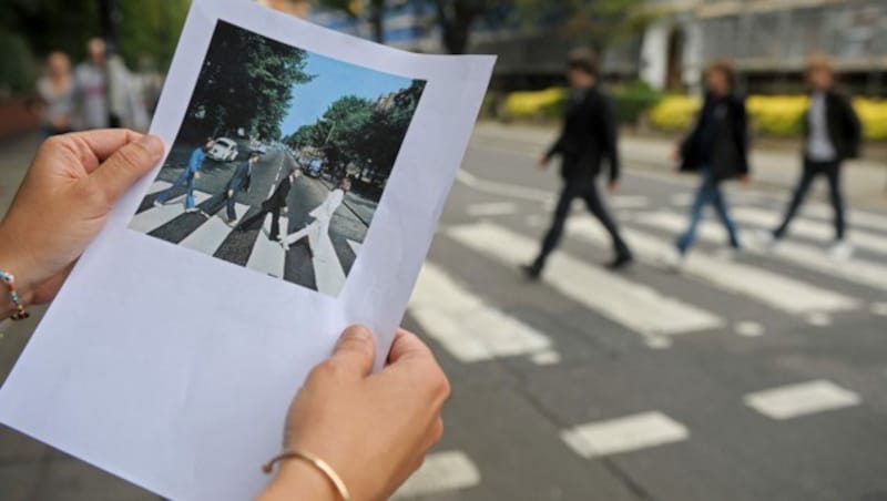 Das berühmte Cover des Beatles-Albums „Abbey Road“ ausgedruckt, im Hintergrund der seither legendäre Zebrastreifen (Bild: AFP/Carl de Souza)