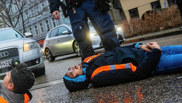 Umweltaktivisten blockieren eine Straße. (Bild: GEORG HOCHMUTH / APA / picturedesk.com)