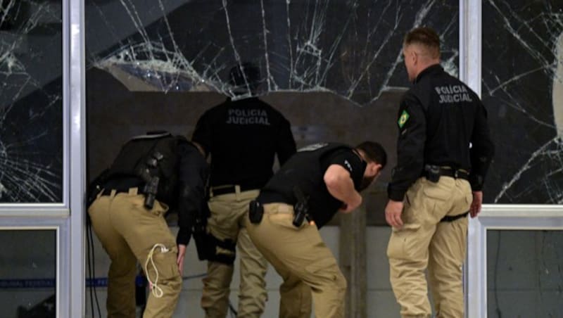 Polizisten inspizieren den Schaden, den Randalierer am 8. Jänner beim brasilianischen Höchstgericht in Brasilia verursacht haben. (Bild: APA/AFP/Carl DE SOUZA)