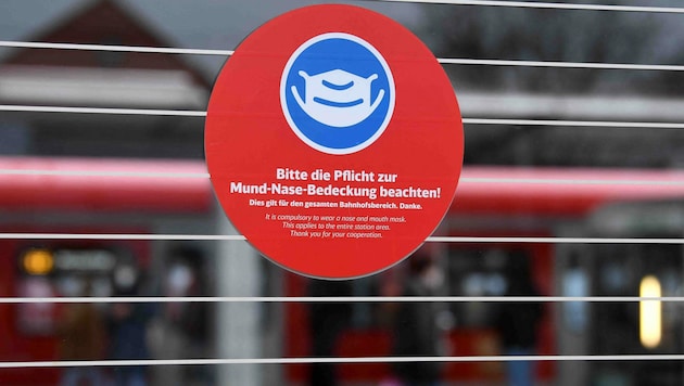 Ein Schild auf einem deutschen Bahnhof mit der Aufforderung an die Reisenden, Mund und Nase mit einer Maske zu bedecken, Diese Regeln fällt am 2. Februar. (Bild: AFP)