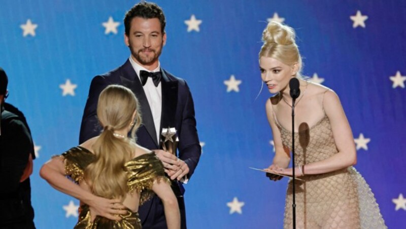 Amanda Seyfried bekommt ihren Award von Miles Teller und Anya Taylor-Joy überreicht. Auf dem Weg auf die Bühne hält sie ihr „brechendes“ Kleid hinten zusammen. (Bild: Kevin Winter/Getty Images for Critics Choice Association/AFP)