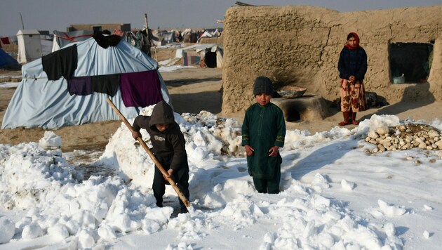 Afghanische Binnenvertriebene schaufeln an einem kalten Wintertag in der Provinz Balkh Schnee in der Nähe ihrer Zelte. (Bild: AFP)