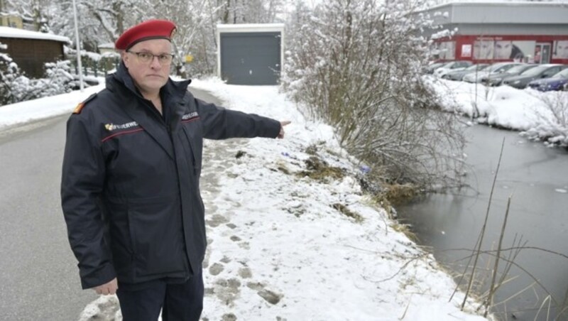 Kommandant Josef Maderegger zeigt die Stelle, an der das Auto im Kühbach versank. (Bild: Manfred Fesl)