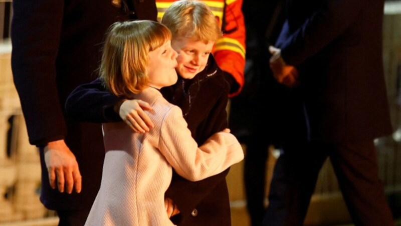 Der monegassische Prinz Jacques und seine Zwillingsschwester Prinzessin Gabriella sind von den Sainte-Devote-Feierlichkeiten 2023 sichtlich angetan und umarmen sich innig im Schein des Feuers. (Bild: APA/Photo by ERIC GAILLARD/AFP)