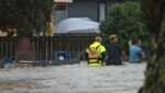 Helfer und ein Mann auf einer überfluteten Straße in Auckland am Freitag (Bild: Hayden Woodward/New Zealand Herald/AP)