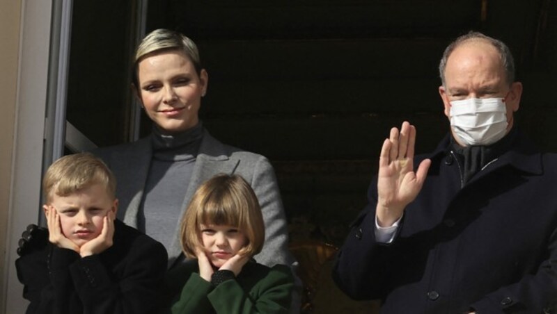 Fürst Albert, der Corona hat, winkt am 27. Jänner 2023, mit seiner Familie vom Balkon des Palastes. (Bild: APA/Photo by Valery HACHE/AFP)