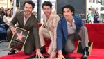 Kevin Jonas, Nick Jonas und Joe Jonas von der US-Band Jonas Brothers posieren für Fotos mit ihrem neu enthüllten Stern auf dem „Hollywood Walk of Fame“ (Bild: APA / Photo by Frederic J. BROWN / AFP)