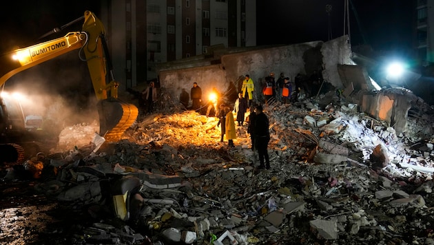 Auch in der Nacht wurde in Adana in der Türkei nach Überlebenden gesucht. (Bild: AP)