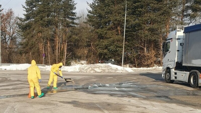 In säurefesten Anzügen und mit Atemschutzmaske brachten die Feuerwehrleute Bindemittel auf den Asphalt auf, um den Gefahrstoff am Weiterfließen zu hindern. (Bild: feuerwehr-villach.at)