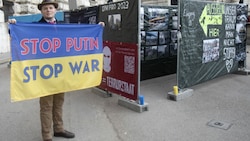 Ein Mann hält eine ukrainische Flagge mit der Aufschrift „Stoppt Putin - Stoppt den Krieg“ vor der Hofburg in Wien. (Bild: AFP or licensors)