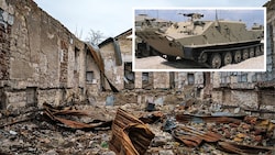 Der Transportpanzer des Typs BTR-50. Im Hintergrund: Das zerstörte Haus der Kultur im ukrainischen Dorf Oleksandriwka in der Region Cherson (Bild: Krone KREATIV,Alexei Stuzhin/Imago APA/AFP/Dimitar DILKOFF)