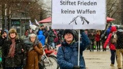 Unter Schnee zeigt ein Demonstrant ein Plakat mit der Aufschrift: „Spendet Frieden, nicht Waffen“. (Bild: AFP)