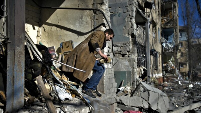 Ein Mann sucht in dem zerstörten Wohnhaus nach Habseligkeiten. (Bild: APA/AFP/Sergey SHESTAK)