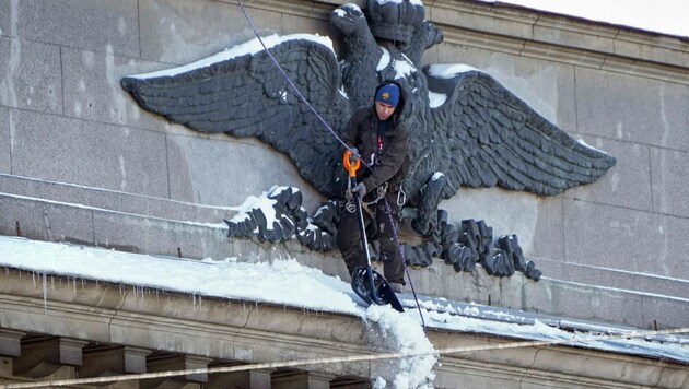 Ein Arbeiter befreit das Wappen auf dem Gebäude der russischen Zentralbank in St. Petersburg von Schnee. (Bild: ASSOCIATED PRESS)