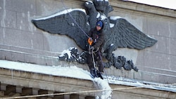 Ein Arbeiter befreit das Wappen auf dem Gebäude der russischen Zentralbank in St. Petersburg von Schnee. (Bild: ASSOCIATED PRESS)