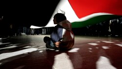 Ein Bub sitzt unter einer Fahne. (Bild: AP Photo/Khalil Hamra)