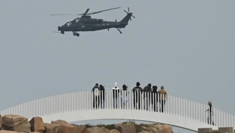 Touristen beobachten einen Militärhubschrauber über Taiwan. (Bild: GREG BAKER / AFP)