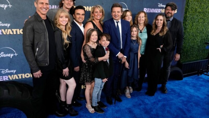 Jeremy Renner ist bei der Premiere umringt von seiner Familie. Tochter Ava (10), rechts neben ihm im blauen Kleid, sei seine „größte Motivatorin“, wieder gesund zu werden, heißt es. (Bild: APA/AP Photo/Chris Pizzello)