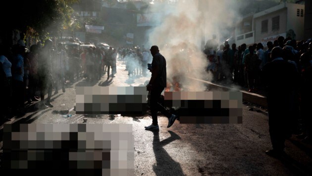 Schaulustige begutachten die verkohlten Leichen der mutmaßlichen Bandenmitglieder. (Bild: AP, Krone KREATIV)