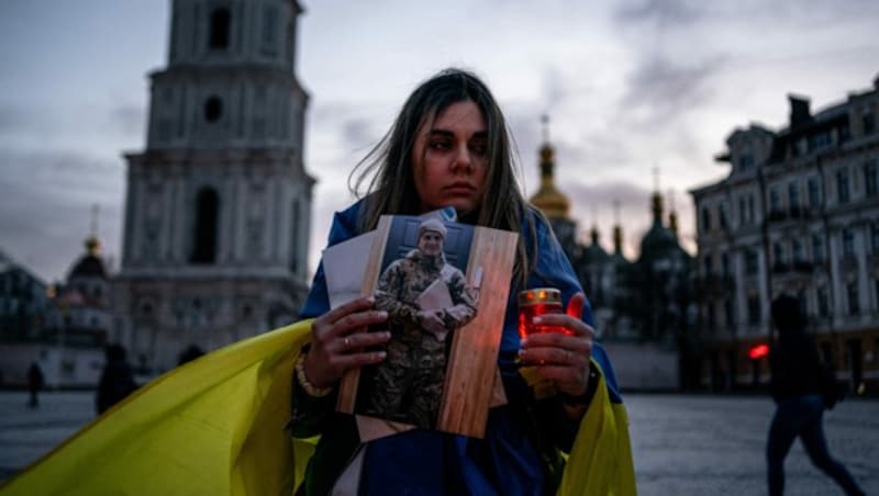 Eine Frau hält eine Kerze und ein Porträt ihres Mannes, der während der Belagerung der Hafenstadt Mariupol gefangen genommen wurde. (Bild: AFP )