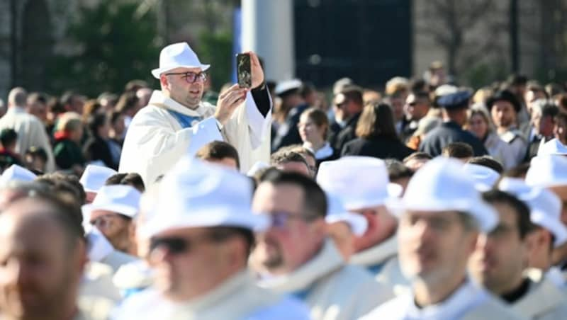 Ein ungarischer Priester macht vor dem Beginn der Abschlussmesse des Papstes Fotos. (Bild: APA/Photo by Vincenzo PINTO / AFP)