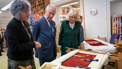 Charles und Camilla begutachten die Thronsitzbezüge während eines Besuchs des Royal College of Needlework im Hampton Court Palace. (Bild: APA/AFP/POOL/Kirsty O‘Connor)